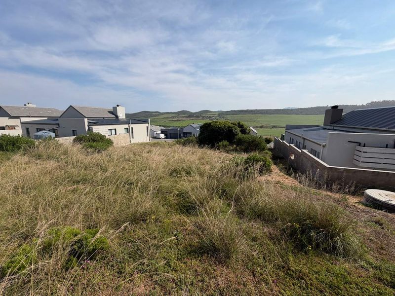 A view of the vacant residential land plot showing surrounding neighborhood development and natural landscape.