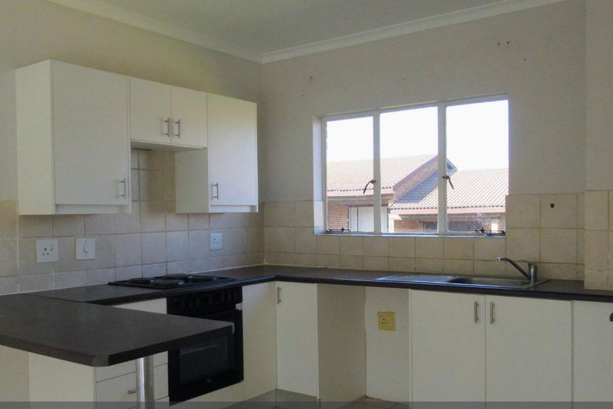 A functional kitchen featuring white cabinetry, dark laminate countertops, a built-in oven and hob, and a tiled backsplash with a window view.