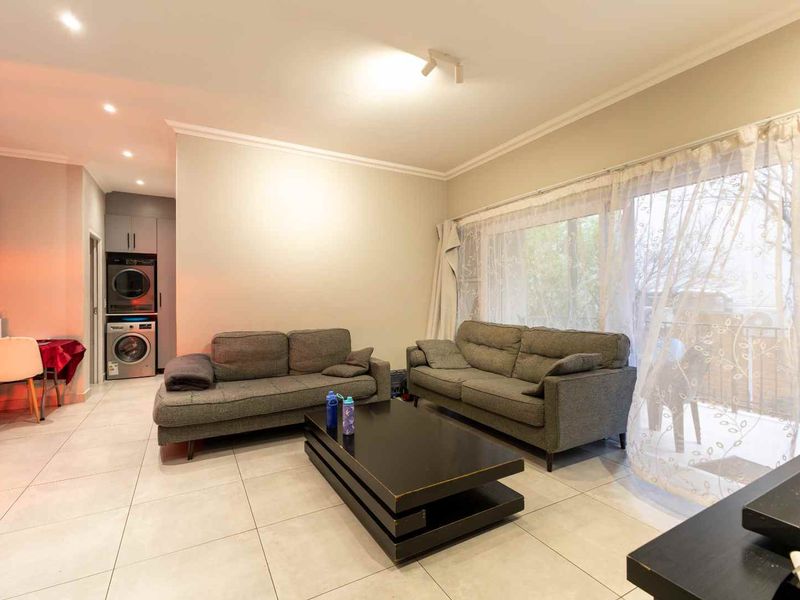 Open-plan living area featuring large format floor tiles, recessed lighting, and a sliding glass door providing access to the balcony.