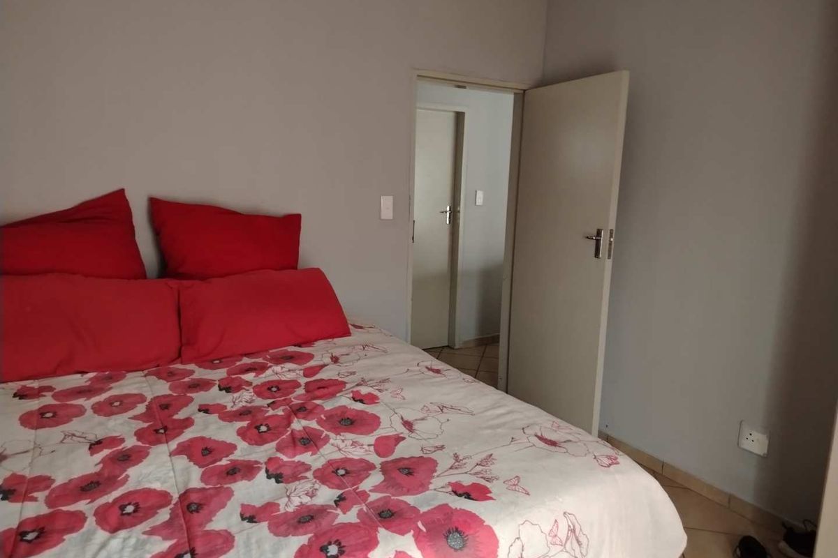 A bedroom featuring tiled flooring and a doorway leading to an adjacent room.