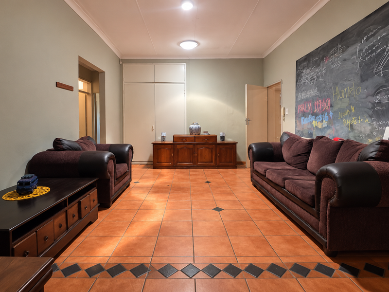 Spacious living room featuring ceramic tile flooring, built-in storage cupboards, and neutral wall finishes, offering a versatile layout for comfortable family living.