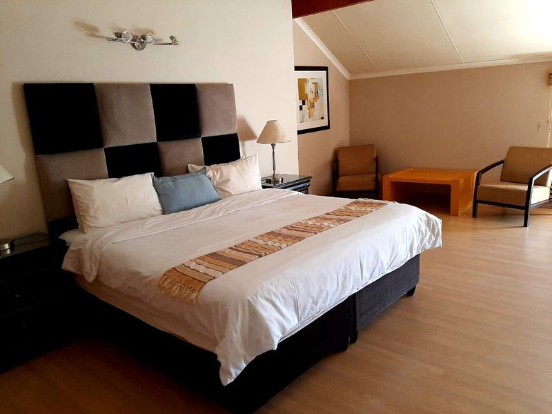 Spacious bedroom featuring laminate flooring and a sloped ceiling, providing a comfortable and well-maintained living space.