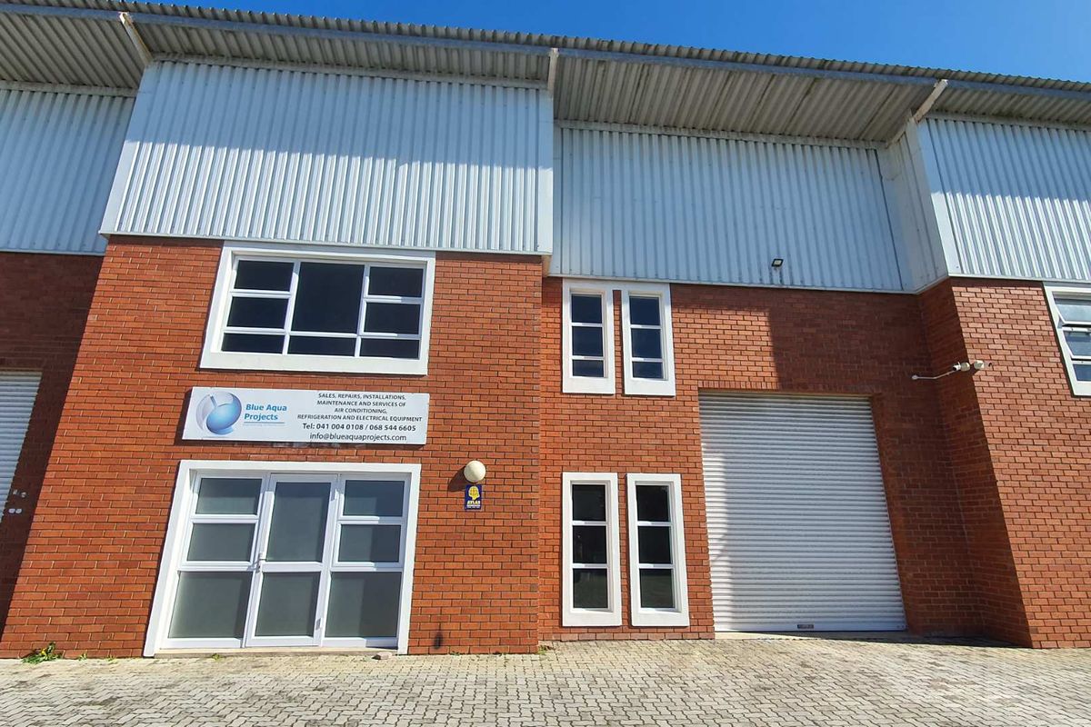 Front elevation of a commercial industrial unit featuring brickwork, corrugated metal cladding, roller shutter access, and aluminium-framed windows.