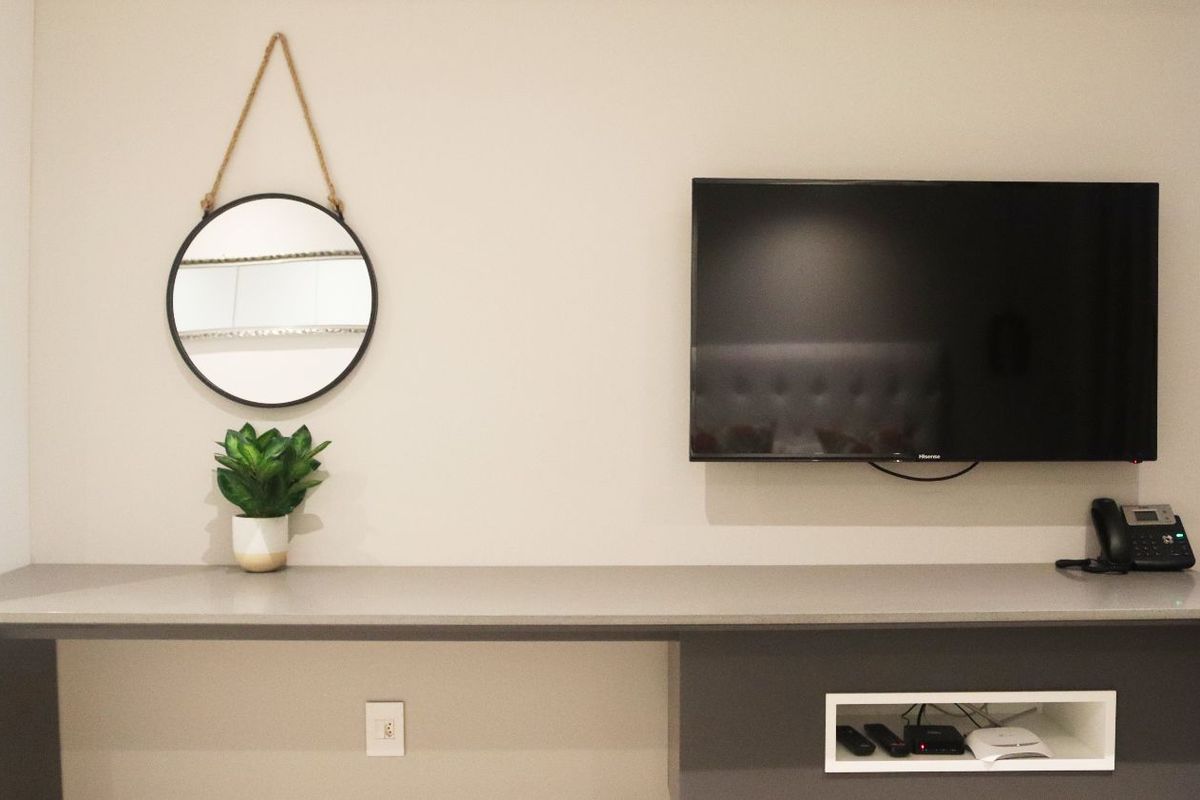 A modern built-in desk or media console featuring a sleek countertop, integrated storage niche, and wall-mounted television setup.
