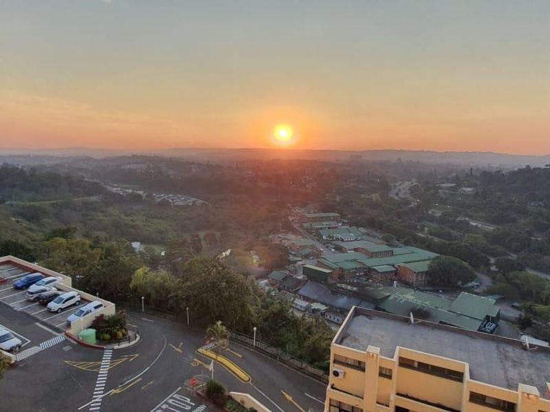 Elevated panoramic view overlooking the surrounding landscape, neighborhood, and parking area at sunset.