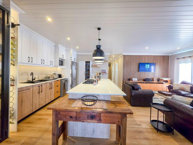 Modern open-plan living area featuring a contemporary kitchen with a large island, gas hob, and a stylish timber slat feature wall.
