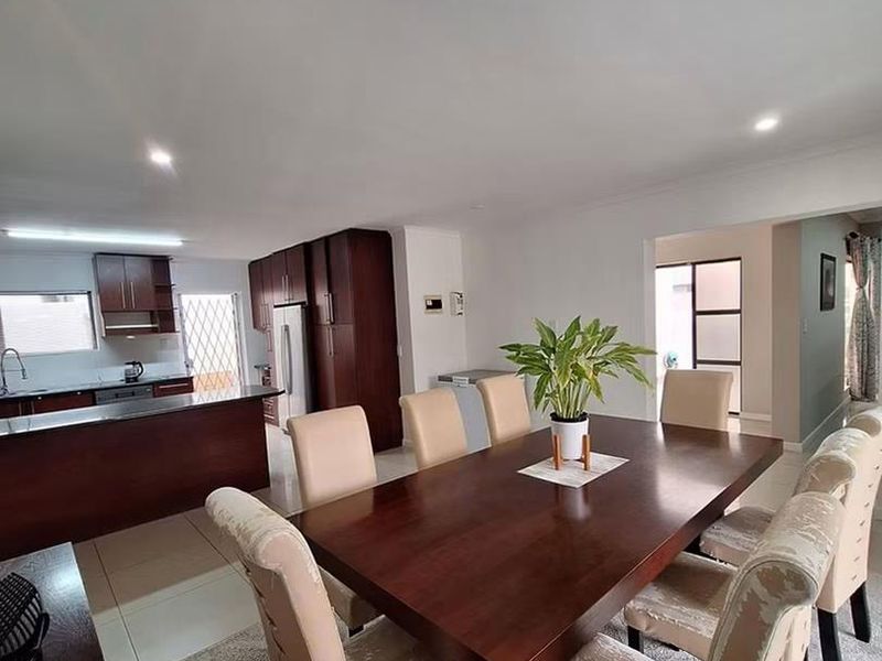 Open-plan living and dining area featuring a functional kitchen with dark wood cabinetry, tiled floors, and recessed lighting, creating a cohesive and spacious layout.