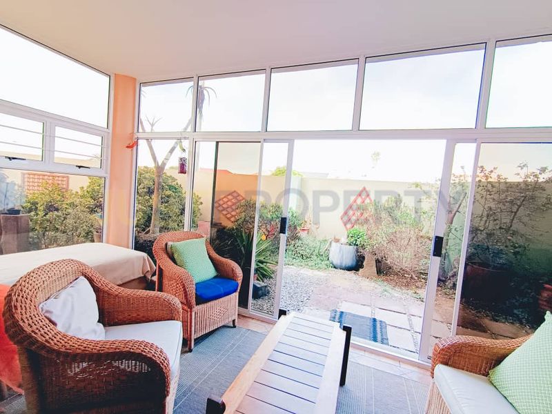 Enclosed patio area featuring large aluminium sliding doors and windows, providing a bright transition space to the rear garden.
