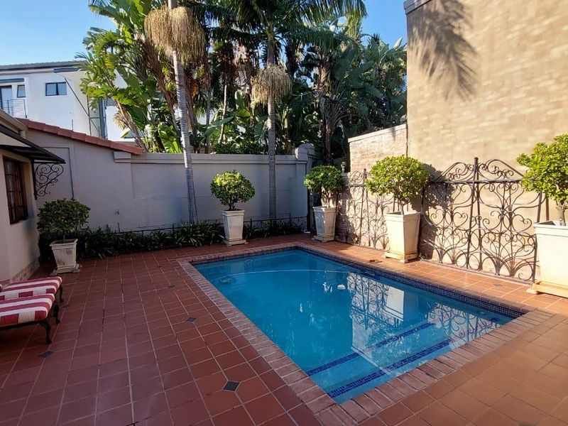 A private outdoor pool area featuring a tiled surround, boundary walls, and decorative wrought iron screening, providing a secluded space for relaxation.