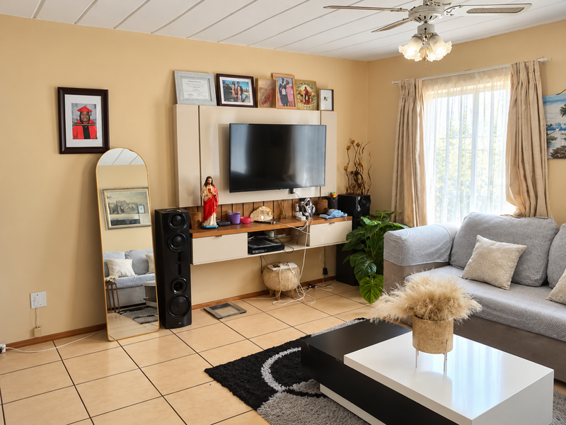 A comfortable living room featuring tiled flooring, a ceiling fan, and a built-in media console, offering a functional and well-lit space.