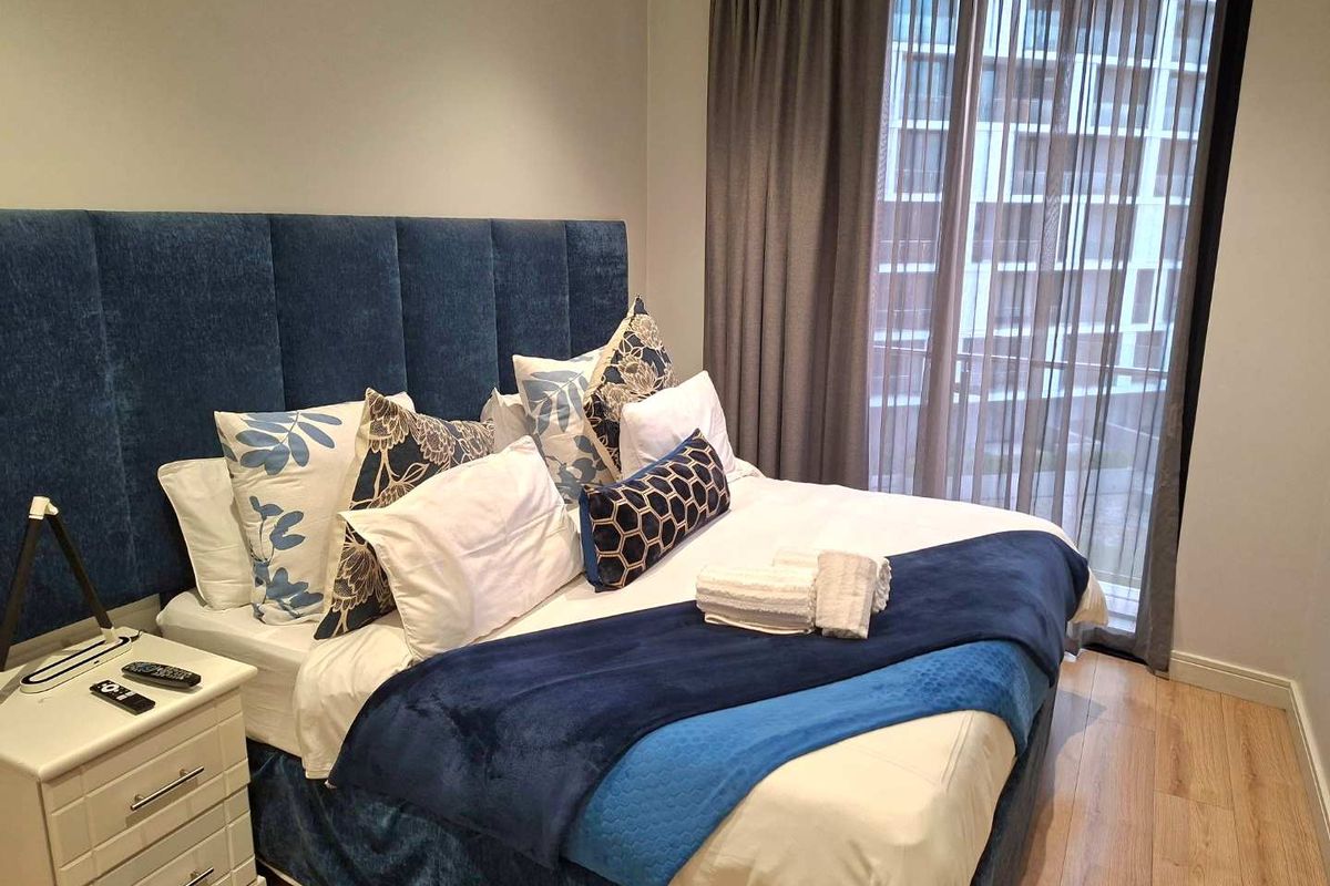 A well-maintained bedroom featuring laminate flooring and a large floor-to-ceiling window with integrated curtain tracks, offering a clean and modern aesthetic.