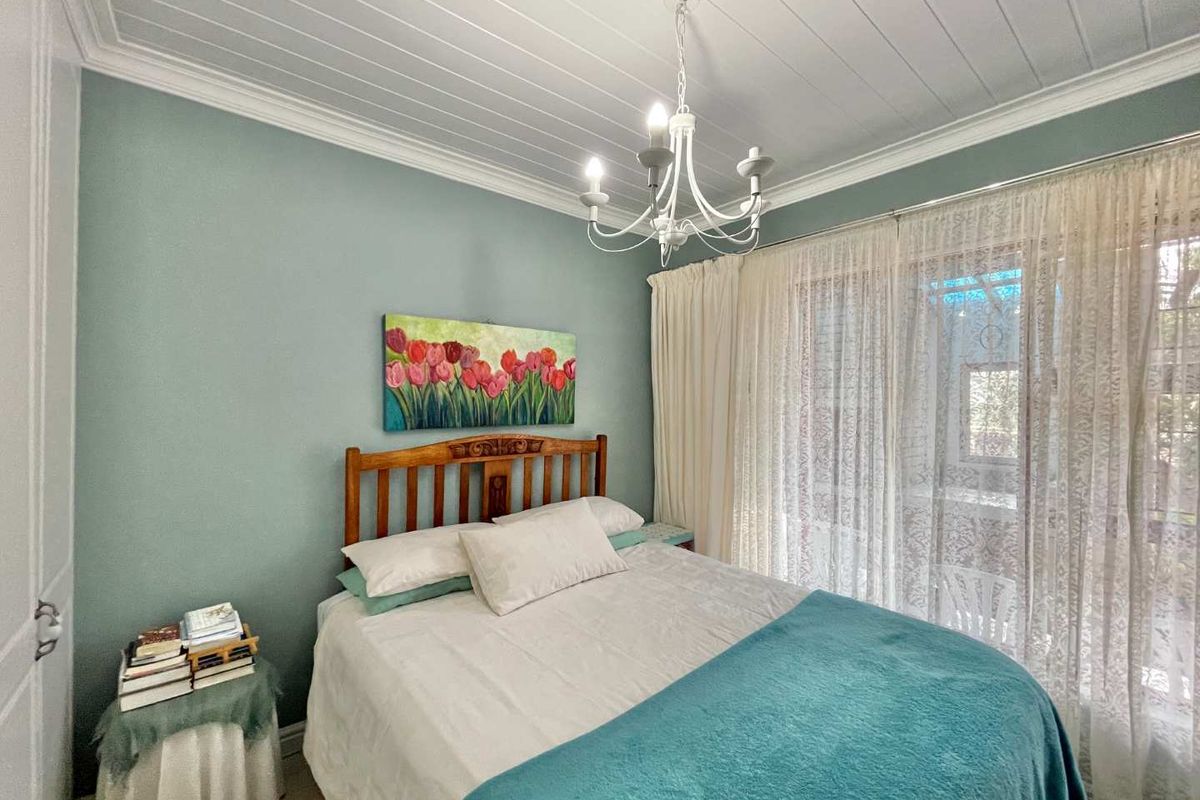 A cozy bedroom featuring a tongue and groove ceiling, crown molding, a decorative chandelier, and a sliding glass door providing natural light.