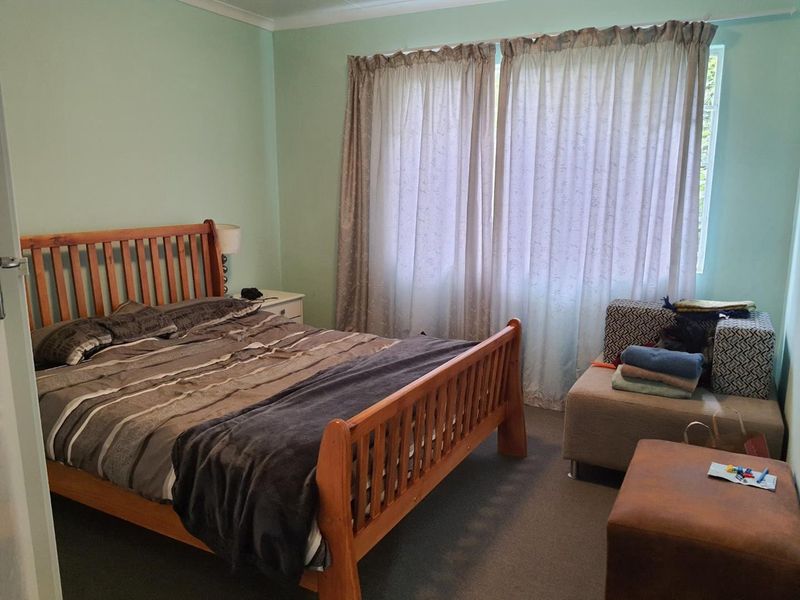 A standard bedroom featuring carpeted flooring and large window with curtain tracks, providing a functional space for rest.