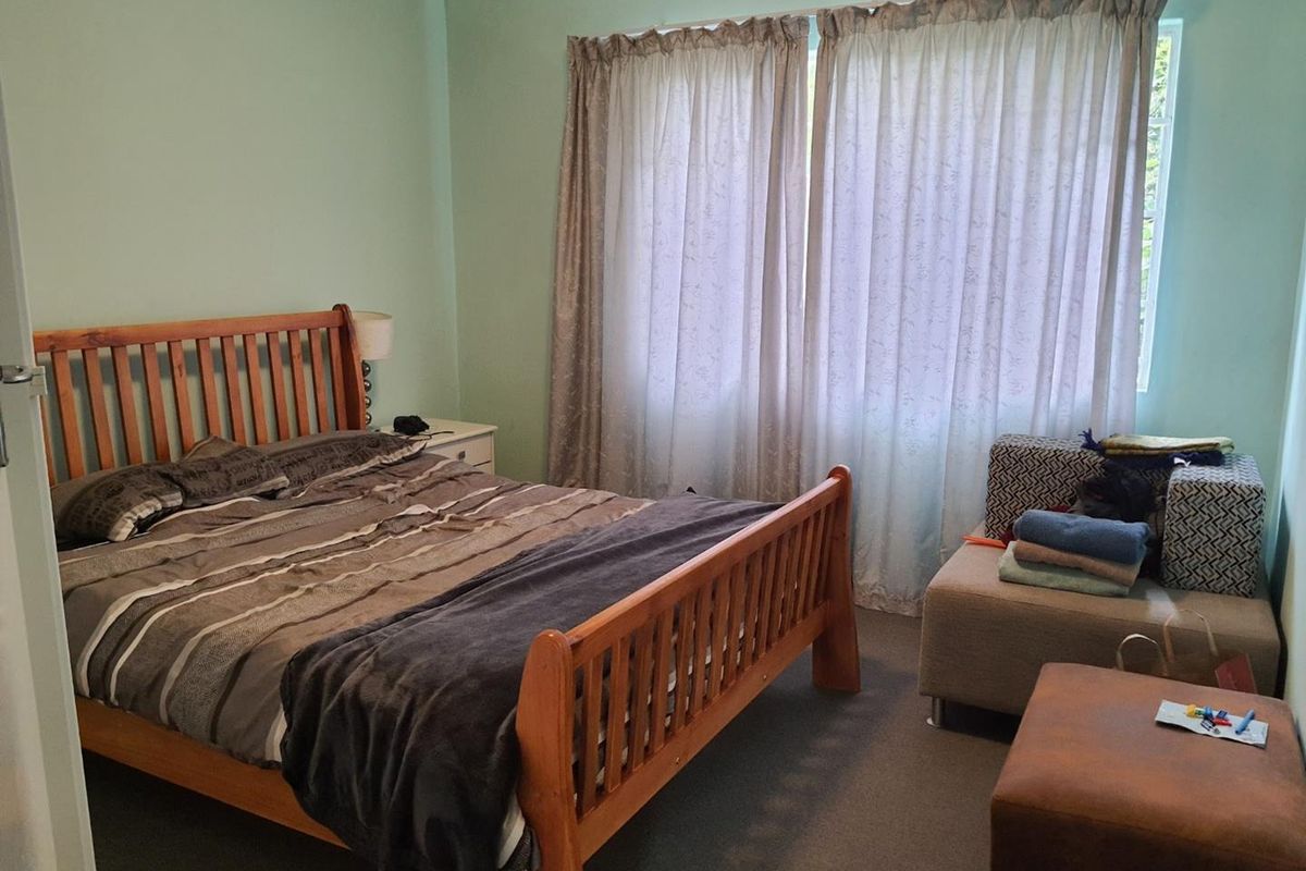A standard bedroom featuring carpeted flooring and large window with curtain tracks, providing a functional space for rest.