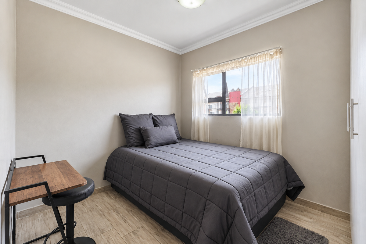A well-maintained bedroom featuring neutral walls, crown molding, tiled flooring, and a built-in wardrobe.