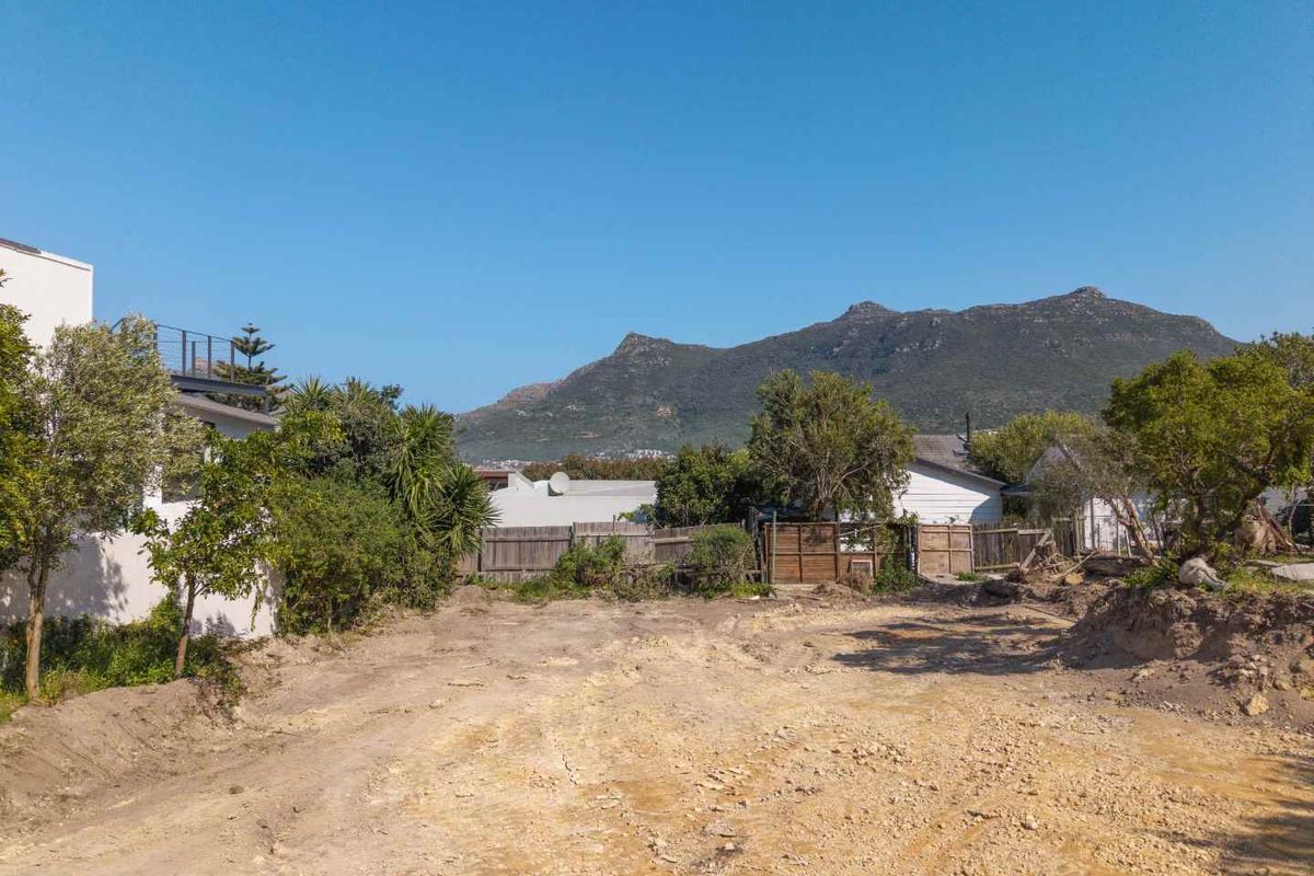 A vacant residential plot featuring natural soil terrain, perimeter timber fencing, and scenic mountain views, offering a blank canvas for development.