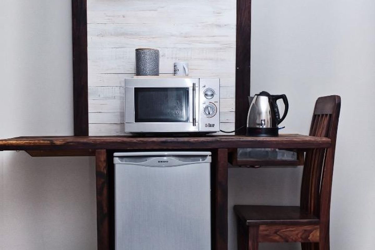 A compact kitchenette area featuring a built-in wooden counter, tiled flooring, and a decorative wood-paneled wall section.