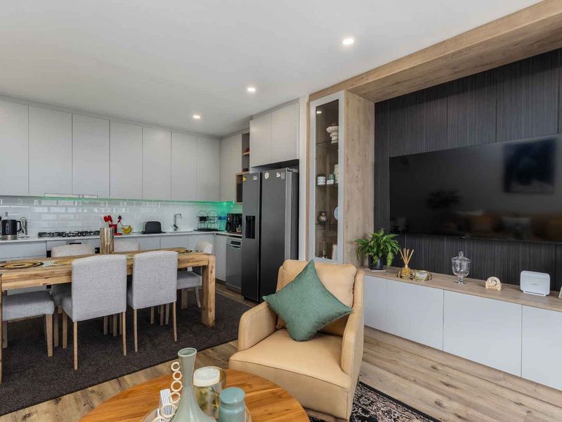 Modern open-plan living area featuring a sleek kitchen with subway tile backsplash, integrated cabinetry, and a custom built-in media wall with wood accents.