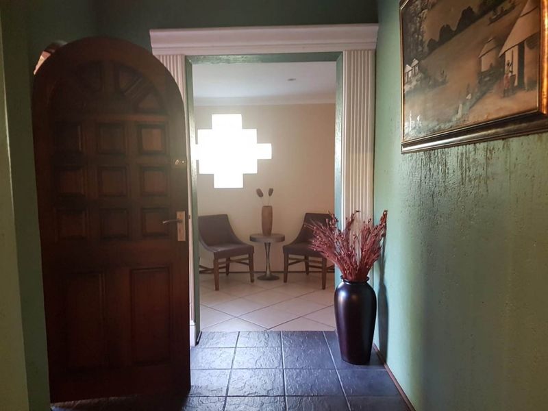 Entryway featuring an arched timber door, fluted door casing, and tiled flooring leading into an adjacent room with a decorative glass block window.
