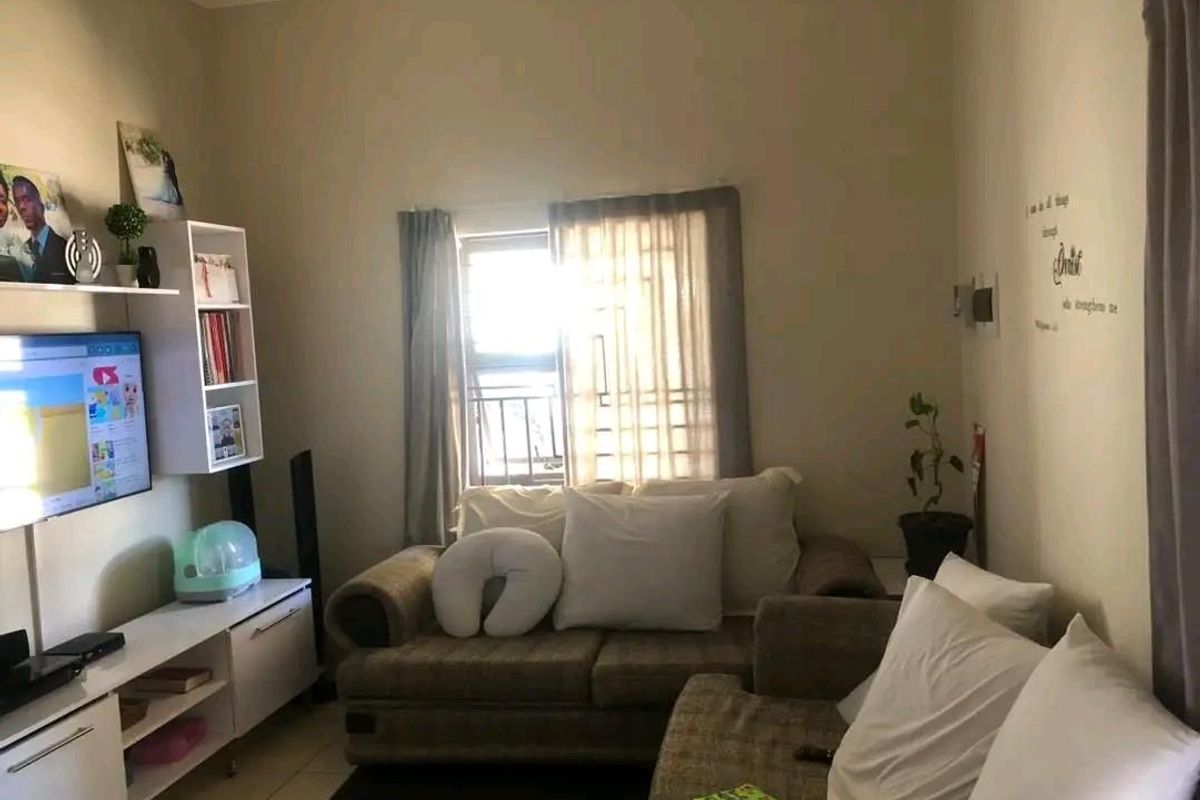 A cozy living room featuring tiled flooring, neutral wall tones, and a window with natural light, providing a comfortable space for relaxation.