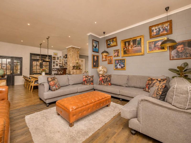 Spacious open-plan living and dining area featuring a stone fireplace, recessed lighting, and durable laminate flooring with direct access through french doors.