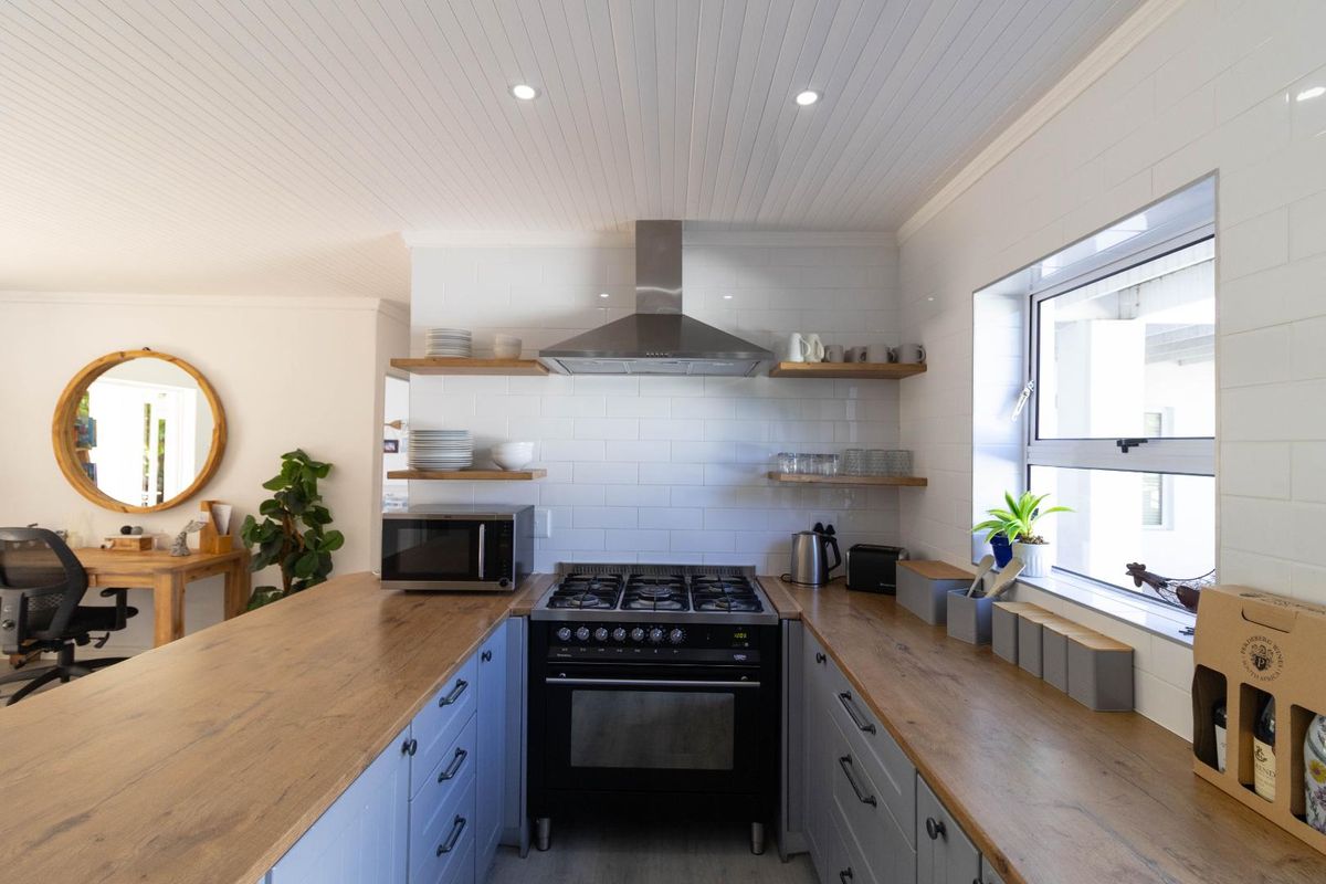Modern kitchen featuring wooden countertops, subway tile backsplash, stainless steel extractor fan, and a built-in gas stove with oven.