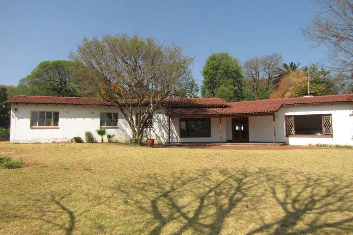 Rear view of a single-story residence featuring a covered patio, terracotta tiled roof, and expansive garden area.
