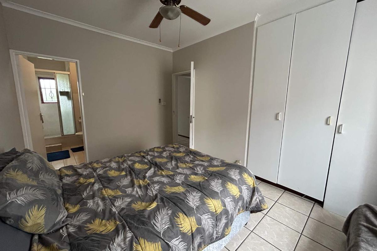 Bedroom featuring built-in cupboards, tiled flooring, a ceiling fan, and an en-suite bathroom access.