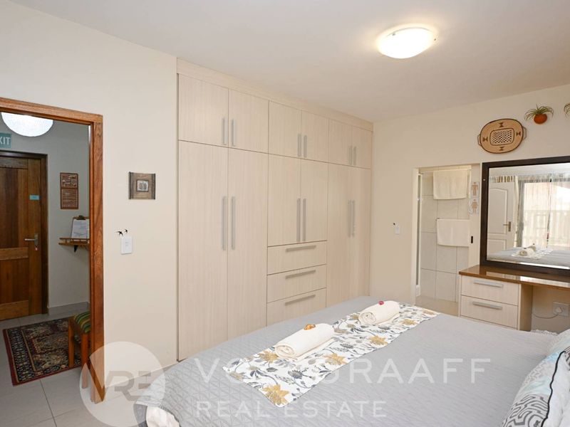 A well-maintained bedroom featuring extensive built-in cabinetry, a matching vanity unit, and direct access to an en-suite bathroom.