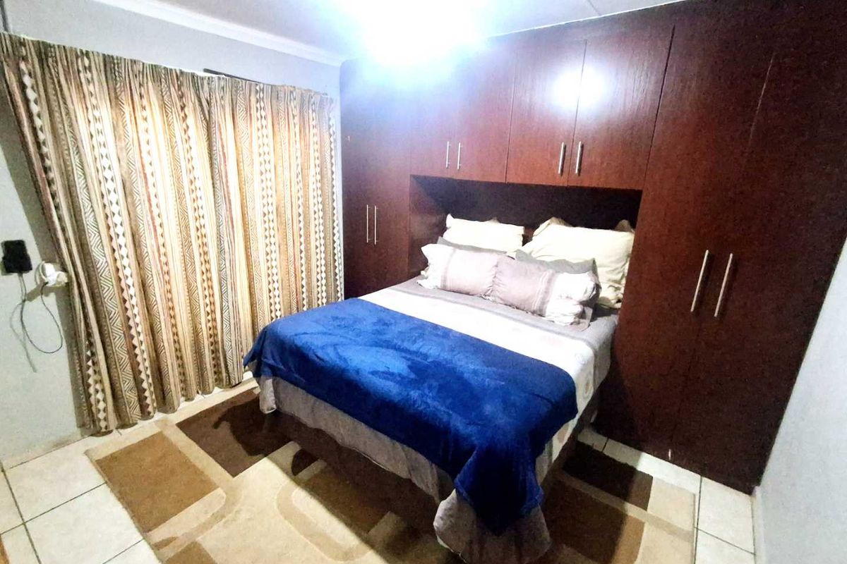 A bedroom featuring dark wood built-in cupboards and tiled flooring, providing functional storage space.