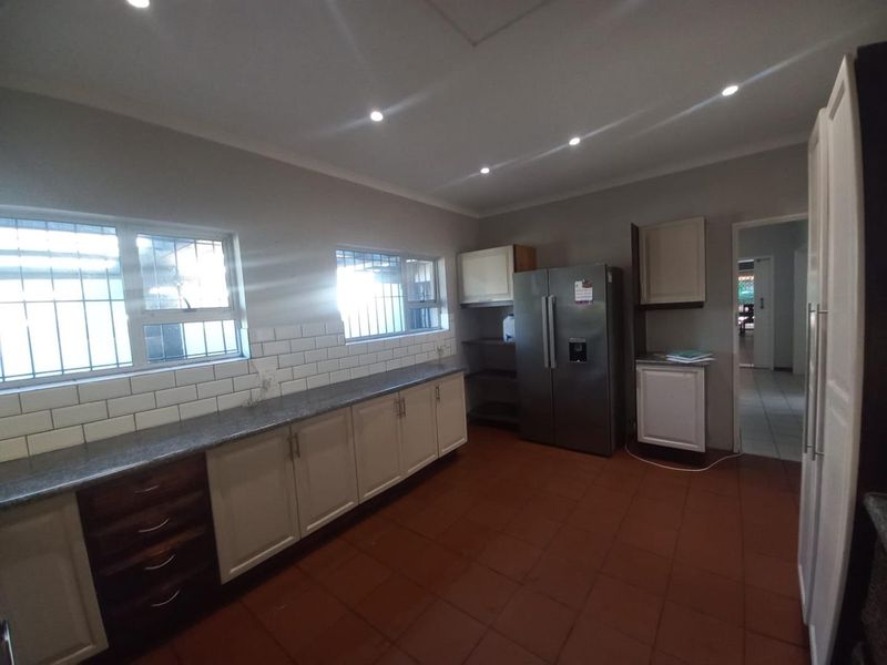 A functional kitchen featuring granite countertops, subway tile backsplash, ample built-in cabinetry, and tiled flooring with recessed lighting.