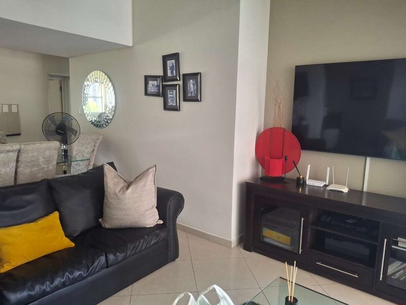 A well-maintained living room featuring neutral tiled flooring and a clean, open layout, providing a comfortable space for relaxation and entertainment.
