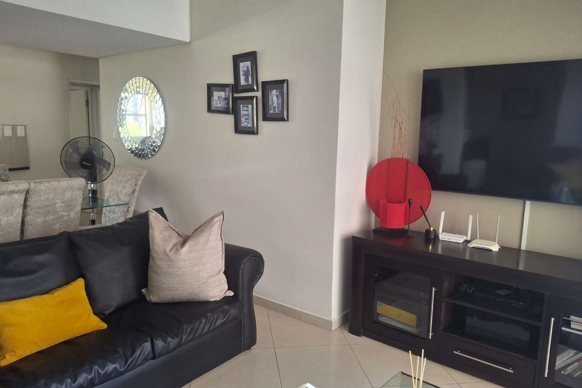 A well-maintained living room featuring neutral tiled flooring and a clean, open layout, providing a comfortable space for relaxation and entertainment.