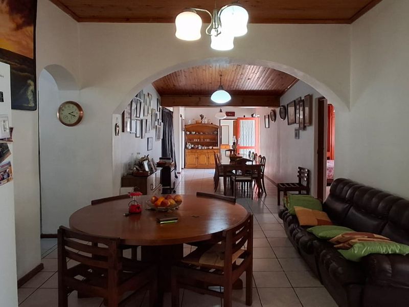 Open plan living and dining area featuring a timber ceiling, tiled flooring, and a central archway connecting the spaces.