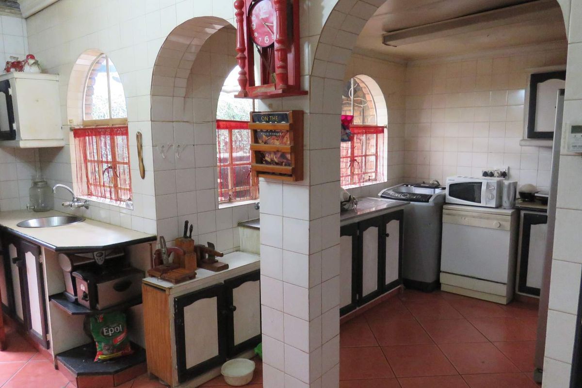 A dated kitchen featuring tiled walls, arched architectural details, and built-in cabinetry with a functional layout.