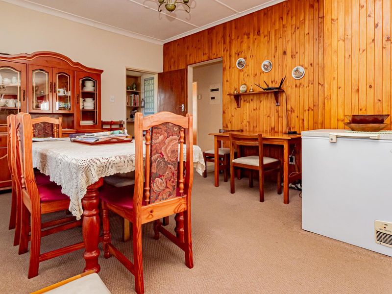 A dining room featuring timber wall paneling, carpeted flooring, and a coved ceiling, offering a traditional aesthetic with potential for modern updates.