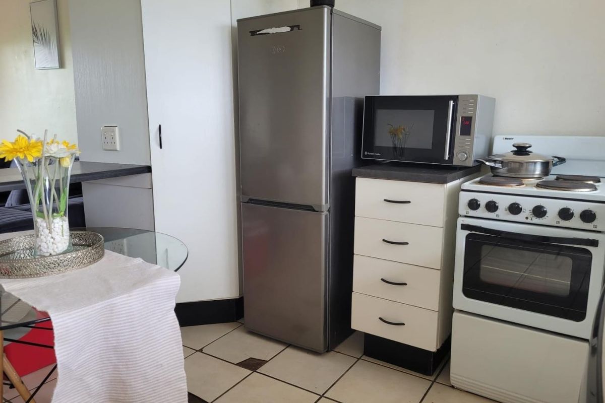 A compact kitchen area featuring tiled flooring, a freestanding stove, and built-in cabinetry, offering a functional layout for an apartment setting.
