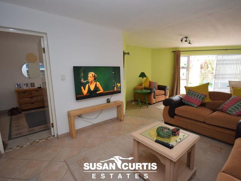 Open plan living area featuring tiled flooring and a sliding glass door with security gate, providing access to the outdoor space.