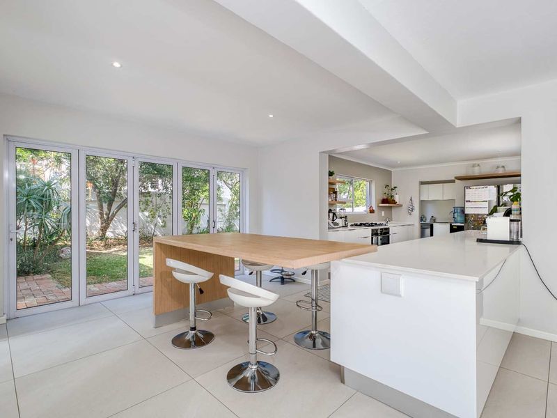 Modern open-plan kitchen and dining area featuring a central island, stone countertops, integrated appliances, and large bi-fold doors opening to the garden.