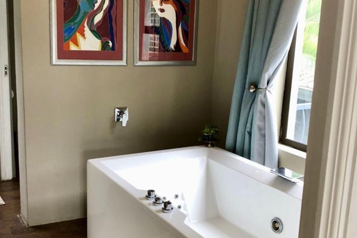 A bathroom featuring a modern built-in bathtub with chrome fixtures and a window providing natural light.