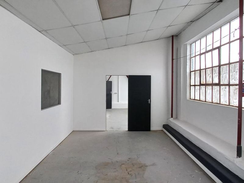 An empty industrial utility space featuring concrete flooring, large steel-framed windows, and a suspended ceiling, suitable for various commercial or storage applications.