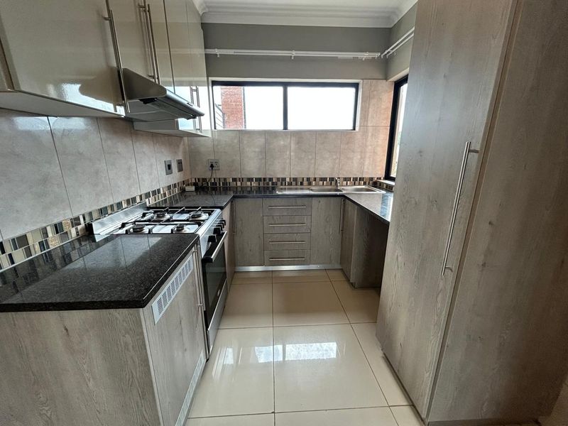 Modern kitchen featuring granite countertops, built-in cabinetry, gas hob, oven, extractor fan, and tiled finishes throughout.