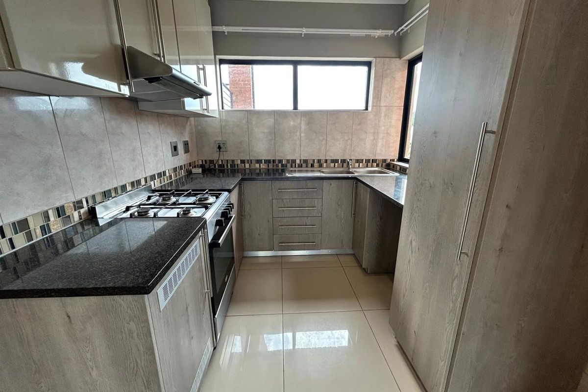 Modern kitchen featuring granite countertops, built-in cabinetry, gas hob, oven, extractor fan, and tiled finishes throughout.
