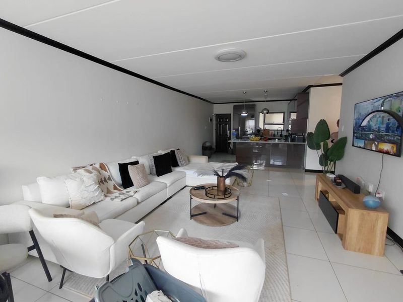 Open-plan living area featuring tiled flooring, a modern kitchen with island, and neutral finishes, creating a spacious and functional layout.