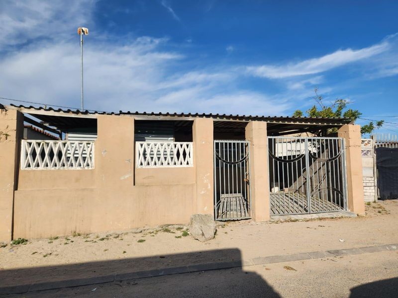 Front exterior view of the property featuring a perimeter wall with decorative breeze blocks and metal security gates.