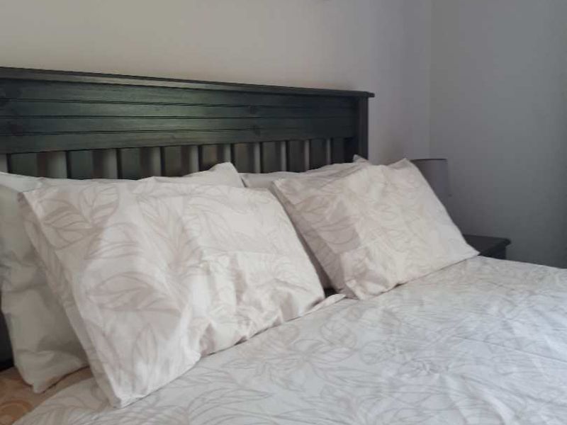 A close-up view of a bedroom featuring a dark wooden headboard and neutral bedding.