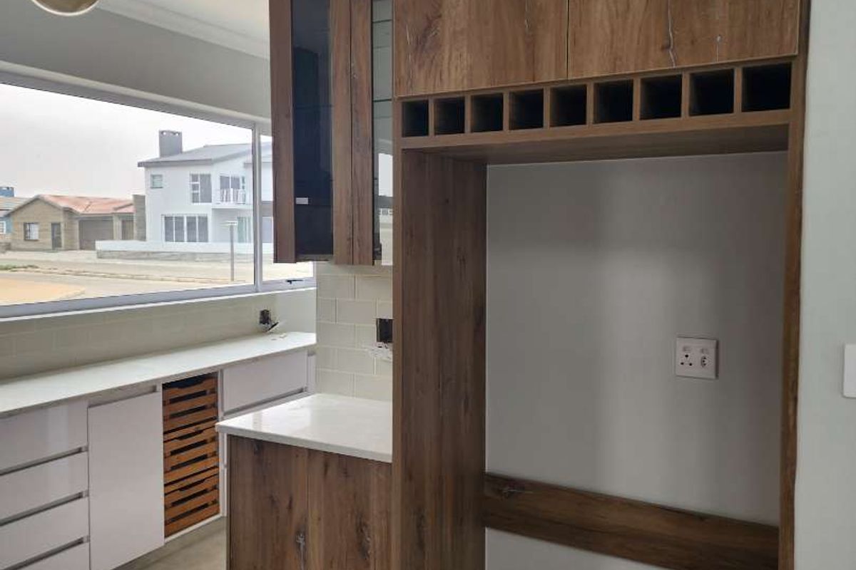 Modern kitchen featuring wood-grain cabinetry, integrated wine rack, stone countertops, and a large window providing natural light and neighborhood views.