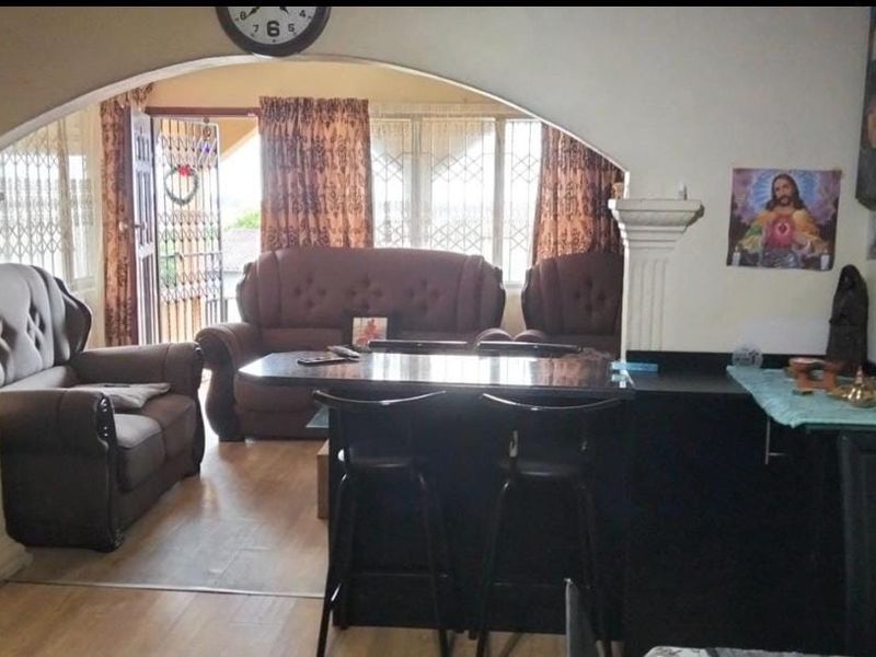 Open plan living area featuring an arched entryway, decorative columns, and a breakfast bar, connecting to a light-filled space with security gate access.