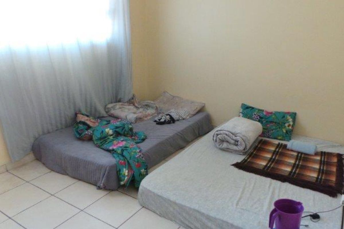 A simple bedroom featuring tiled flooring and neutral wall finishes, providing a functional space for rest.