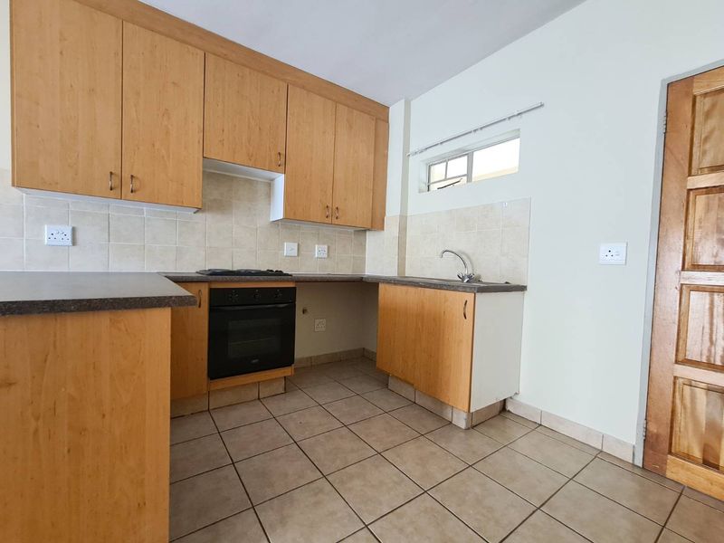 A functional kitchen featuring light wood laminate cabinetry, built-in oven, gas hob, tiled backsplash, and tiled flooring, offering a clean and practical workspace.